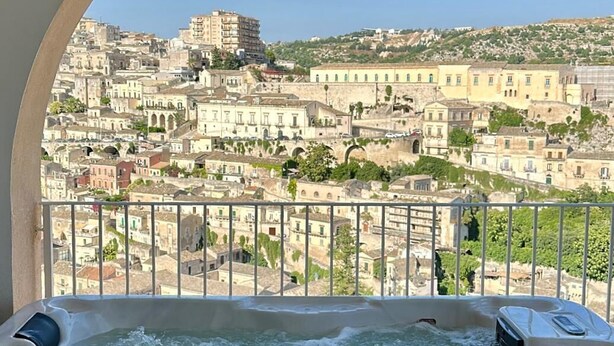 A hot tub with a view of a cityscape through an arched window. - Itria Modica (Modica)