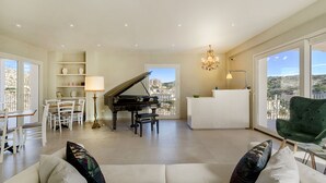 A spacious living room with a grand piano, a white sofa, and a green armchair. - Itria Modica (Modica)