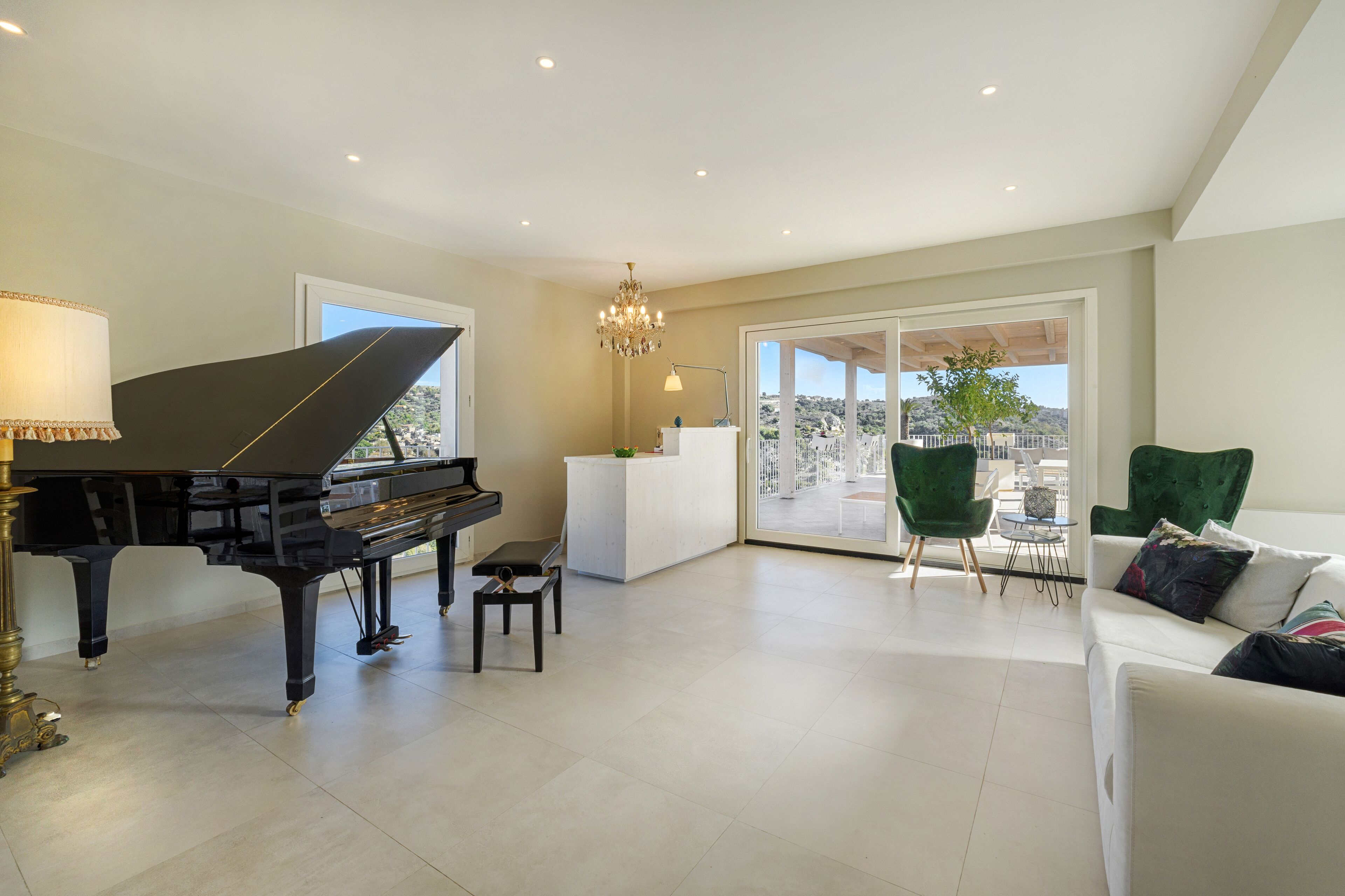 A spacious living room with a grand piano, a white sofa, and a green armchair.