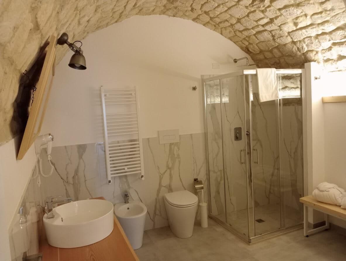 A bathroom with a stone ceiling, a glass shower enclosure, a white sink, and a toilet.