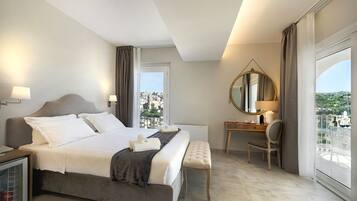 A hotel room with a large bed, a desk, a chair, a mirror, and a view of the city.