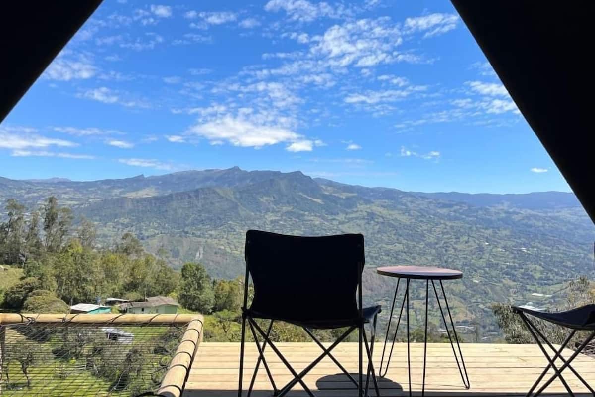 A view from a covered outdoor area with a wooden deck, two chairs, and a table.