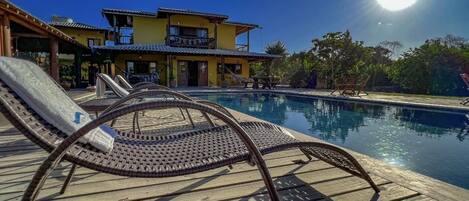 A pool area with lounge chairs and a building in the background.