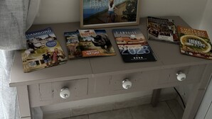 A desk with a framed poster of Chenevaux, a collection of travel brochures, and a door with a handle.