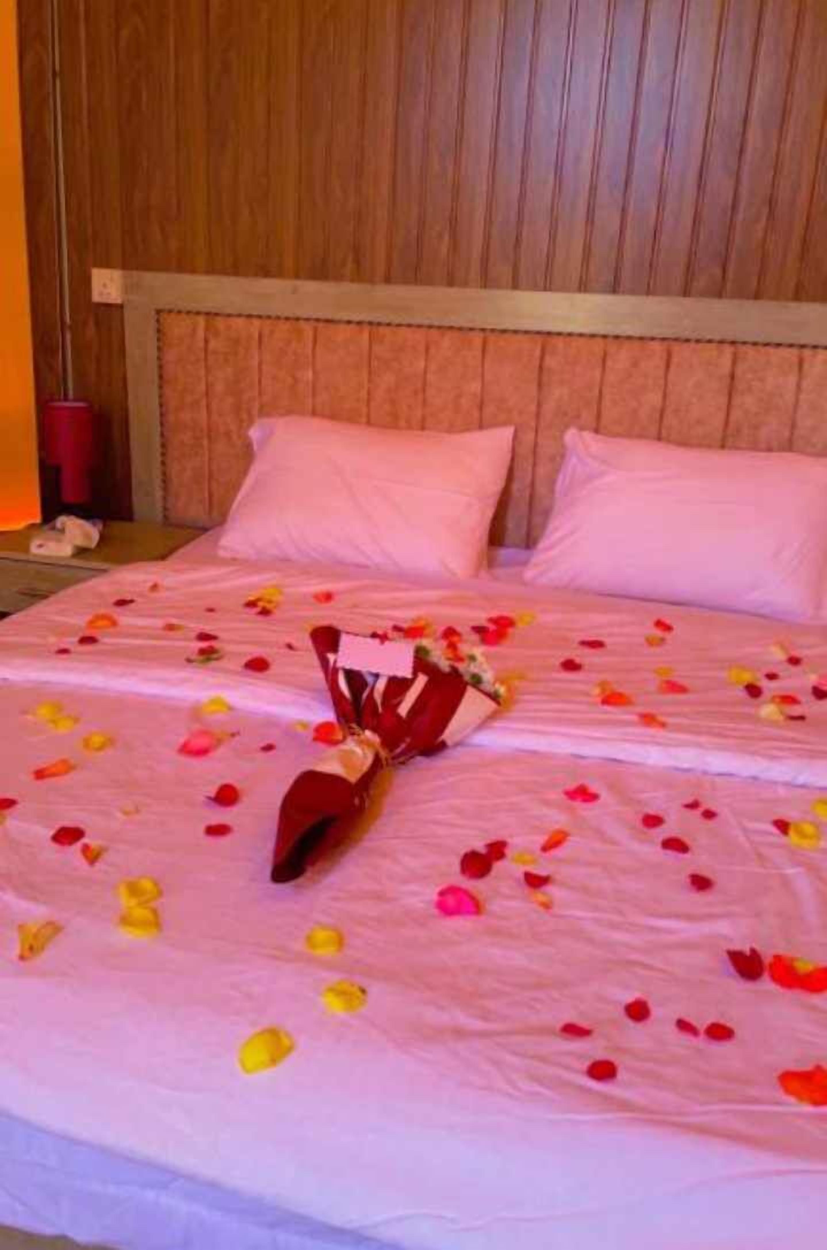 A hotel room with two beds, each with a pink bedspread and pillows.