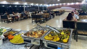 A buffet-style dining area with multiple food stations and seating arrangements. - Abdullah Ram  (Wadi Rum)