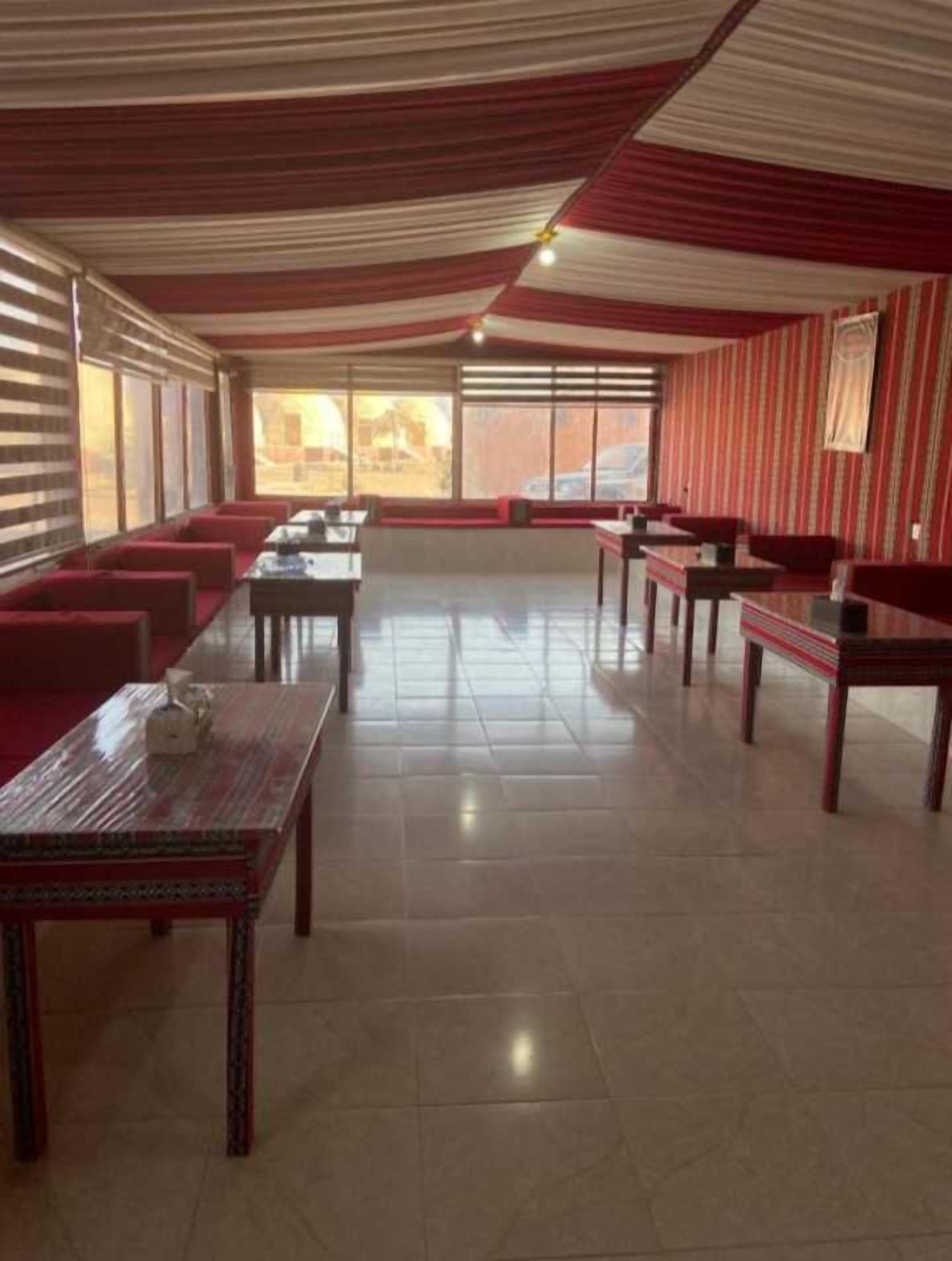 Un vaste espace dédié à la salle à manger, avec des sièges et des tables à revêtement rouge, de grandes fenêtres et un plafond à rayures.