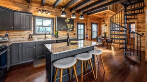 A spacious kitchen with a large island, dark cabinets, and a wooden ceiling.