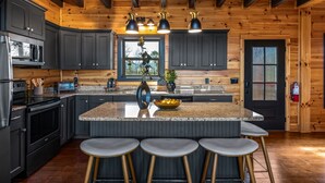 A modern kitchen with dark cabinets, granite countertops, and a central island with stools.