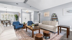 A modern living room with a sofa, armchairs, a coffee table, and ottomans. - Leafy Lodge, Near Springs, Beach, Hot Tub, Fenced (Spring Hill)