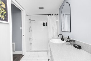 A modern bathroom with a shower, sink, and mirror. - Leafy Lodge, Near Springs, Beach, Hot Tub, Fenced (Spring Hill)