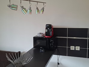 A kitchen with a microwave, coffee maker, and hanging lights.