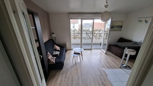 Una sala de estar moderna con un sofá, una mesita redonda y un balcón con vistas.