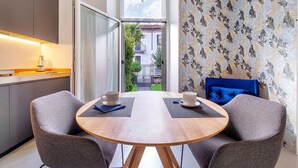 Een moderne kamer met een houten tafel, twee stoelen, uitzicht op een balkon en behang met een patroon.