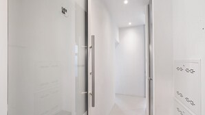 Een modern interieur met een glazen deur, een metalen handgreep en een witte muur met een geometrisch patroon.