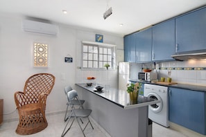 A kitchen with a washing machine, a dining area with chairs, and a decorative wall piece. - Apartment 'Lemons' with Private Terrace, Wi-Fi and Air Conditioning (Carvoeiro)