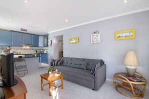 A living room with a sofa, a coffee table, a television, and a dining area with a chair and table. - Apartment 'Lemons' with Private Terrace, Wi-Fi and Air Conditioning (Carvoeiro)