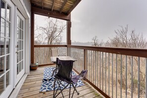 A covered outdoor deck with a table and chairs, a blue patterned rug, and a view of leafless trees and a distant city skyline. - King Bed - 2 BR Apt with City Views. Pet friendly. Free parking! (Pittsburgh)