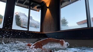 A person swimming in a pool with large windows overlooking a snowy mountain landscape. - Chalet 'Aikoa' with Mountain View, Private Terrace and Wi-Fi (Chamonix-Mont-Blanc)