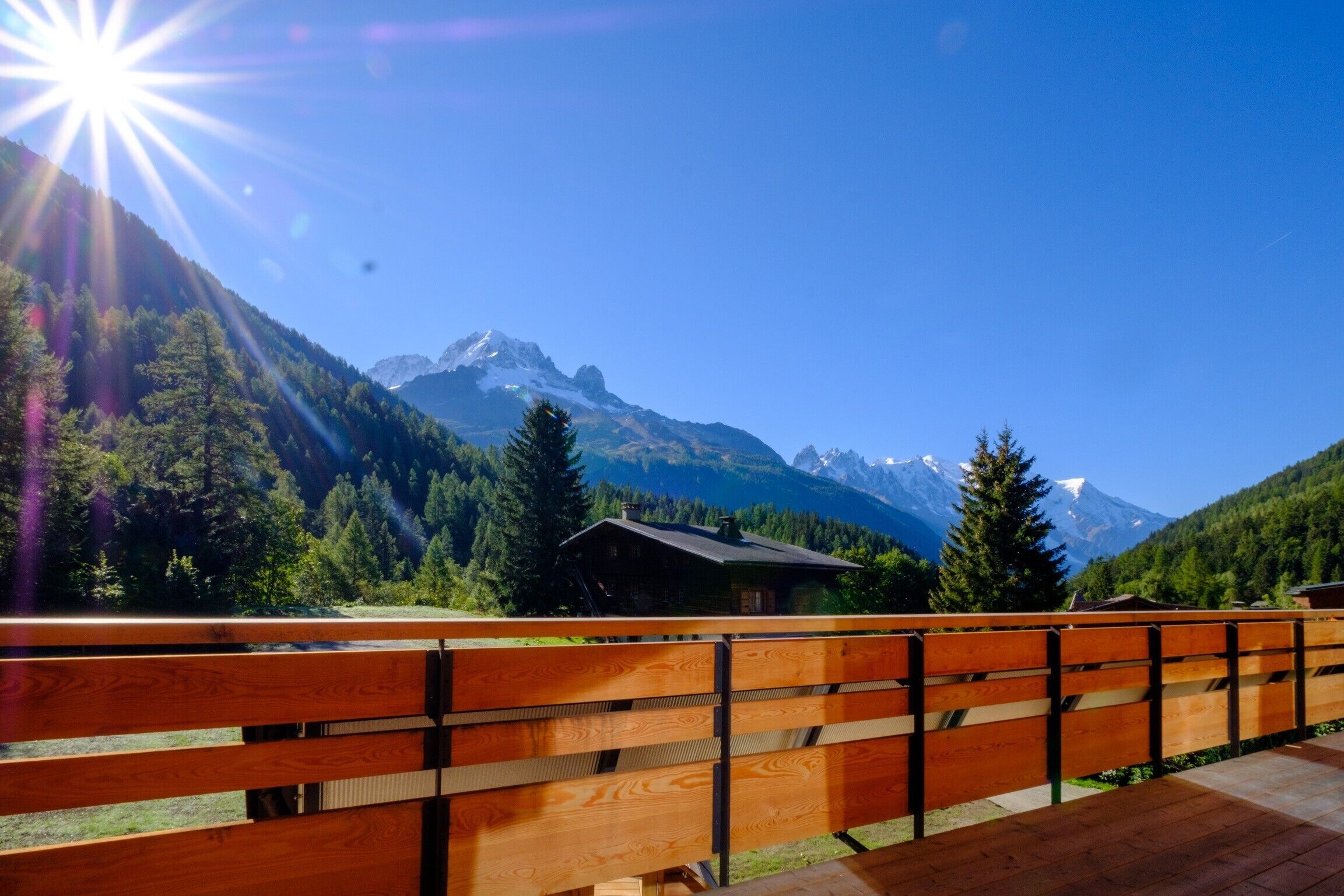 Eine Holterrasse mit Bergblick, eine kleine Hütte und klarer Himmel.