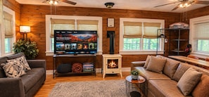 A cozy living room with a television, a fireplace, and comfortable seating. - Romantic Fall Foliage Couples Escape | Hot Tub, EV Charger, 600 Mbps (Mars Hill)