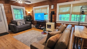 A cozy cabin interior with a wooden interior, a fireplace, a television, and a dining area. - Romantic Fall Foliage Couples Escape | Hot Tub, EV Charger, 600 Mbps (Mars Hill)