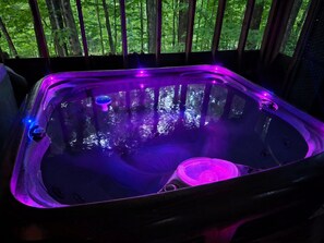 A hot tub with a view of a forest through a wooden railing. - Romantic Fall Foliage Couples Escape | Hot Tub, EV Charger, 600 Mbps (Mars Hill)