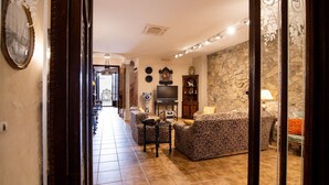 A living room with a sofa, a television, a fireplace, and a stone wall.