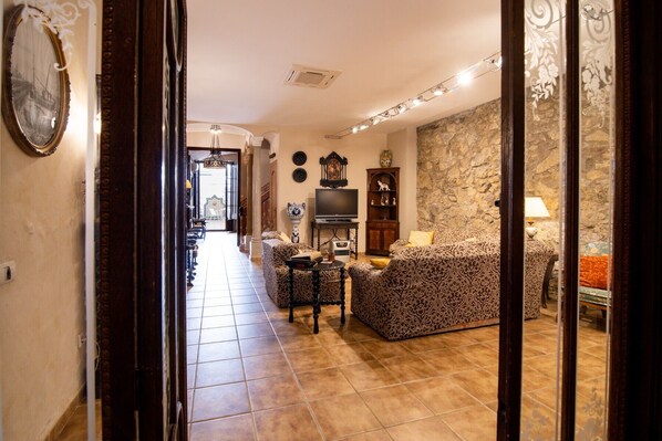 A living room with a sofa, a television, a fireplace, and a stone wall.
