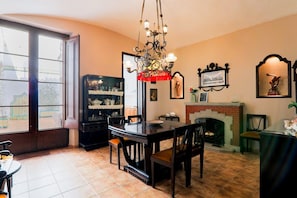 Comedor con candelabro, chimenea y un ventanal grande.