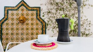 A table with a white cup, a black coffee pot, and a woven placemat.