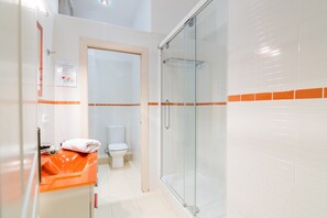 Un baño con cabina de ducha de vidrio, inodoro y lavabo con toalla.