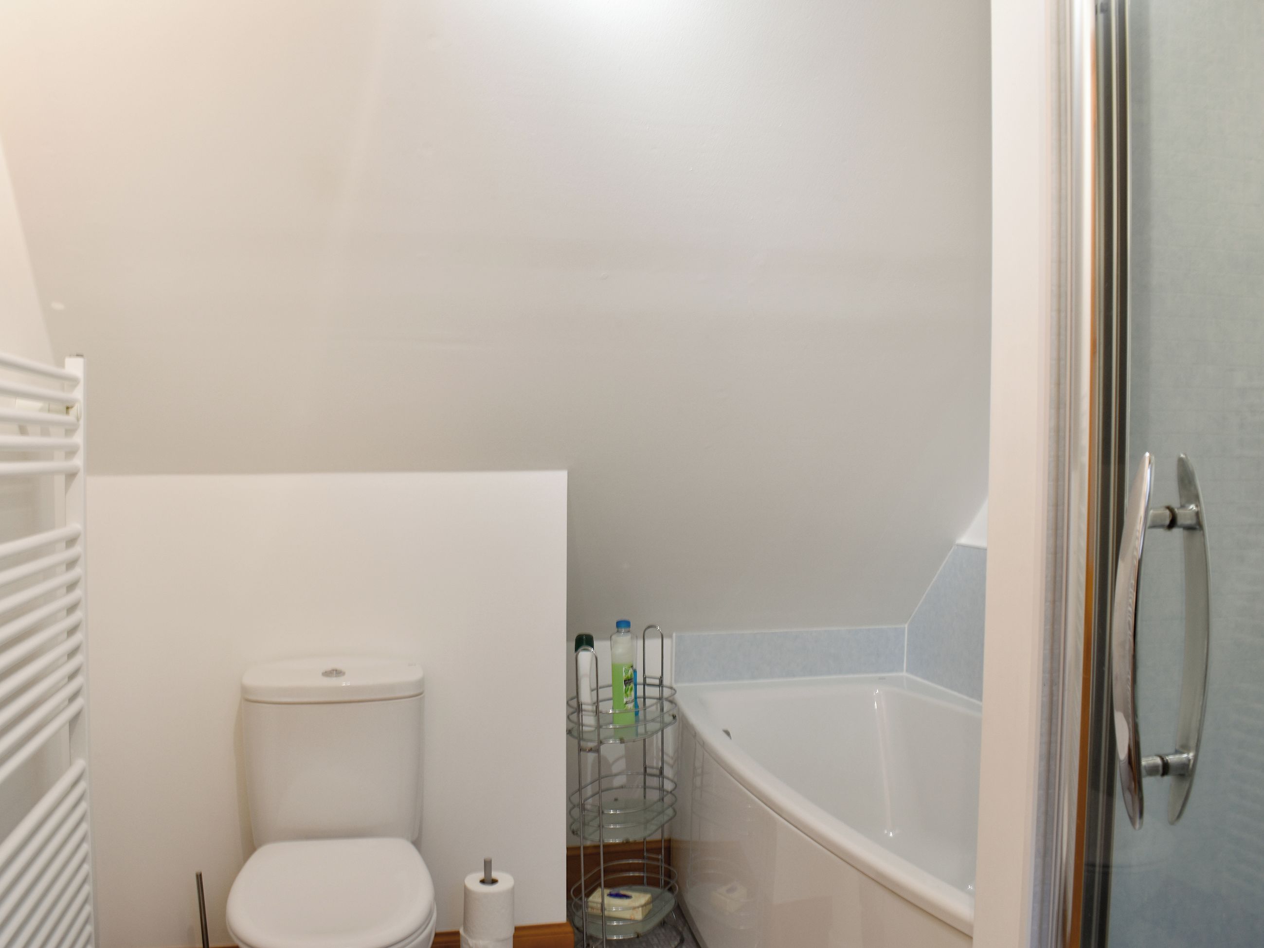 Ein kleines Badezimmer mit Toilette, einer Duschkabine aus Glas und einer weißen Badewanne.