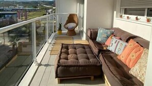 Un balcone con divano e poltrona, vista sulla città e una montagna sullo sfondo.
