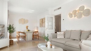 Una sala moderna con sofá, una mesita de centro y una zona de comedor.