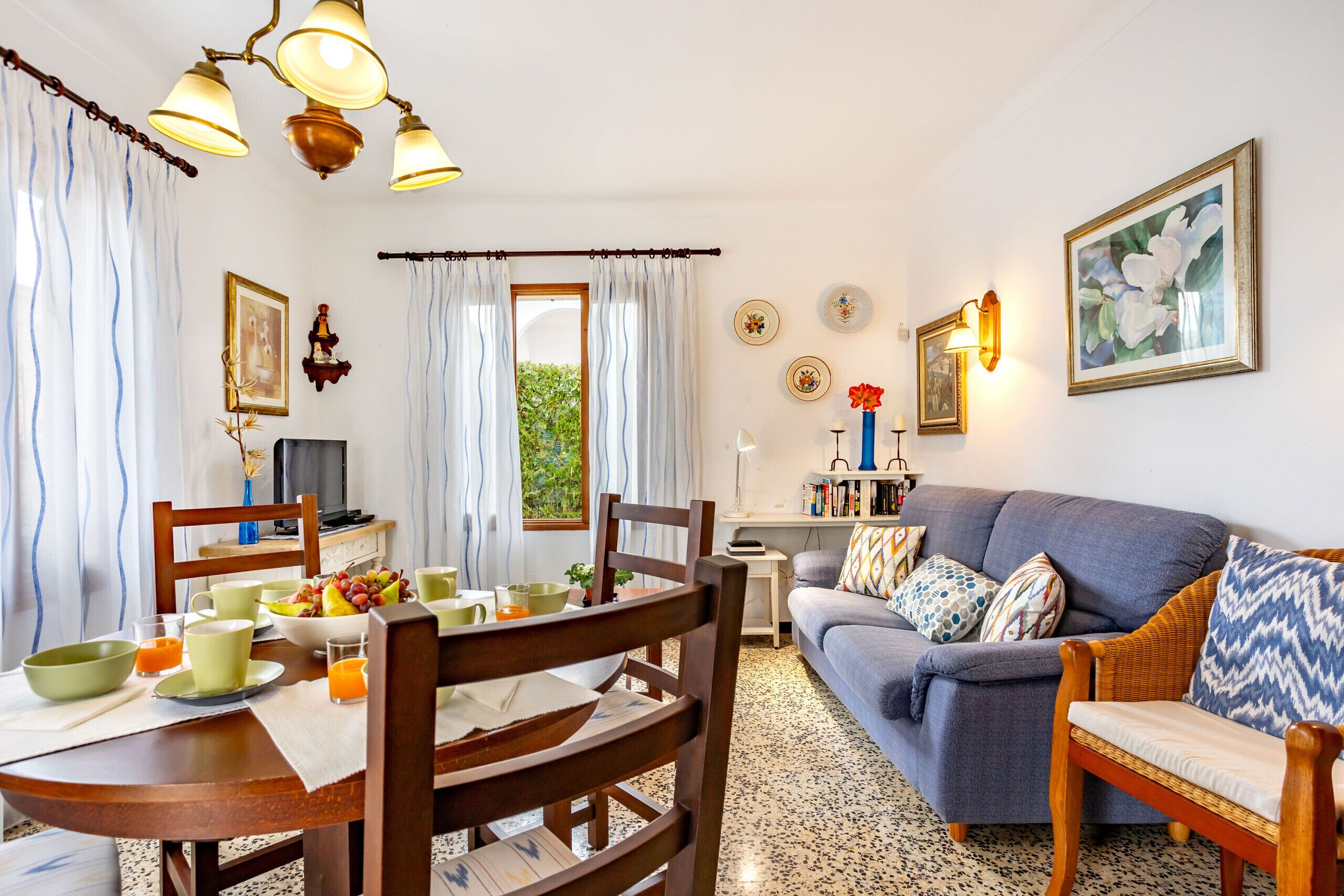 Una sala de estar acogedora con sofá, mesa de comedor, sillas y televisor.