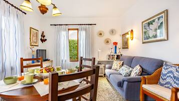Una sala de estar acogedora con sofá, mesa de comedor, sillas y televisor.