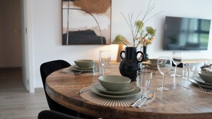 Een eettafel gedekt met kommen, glazen en bestek, omringd door stoelen.
