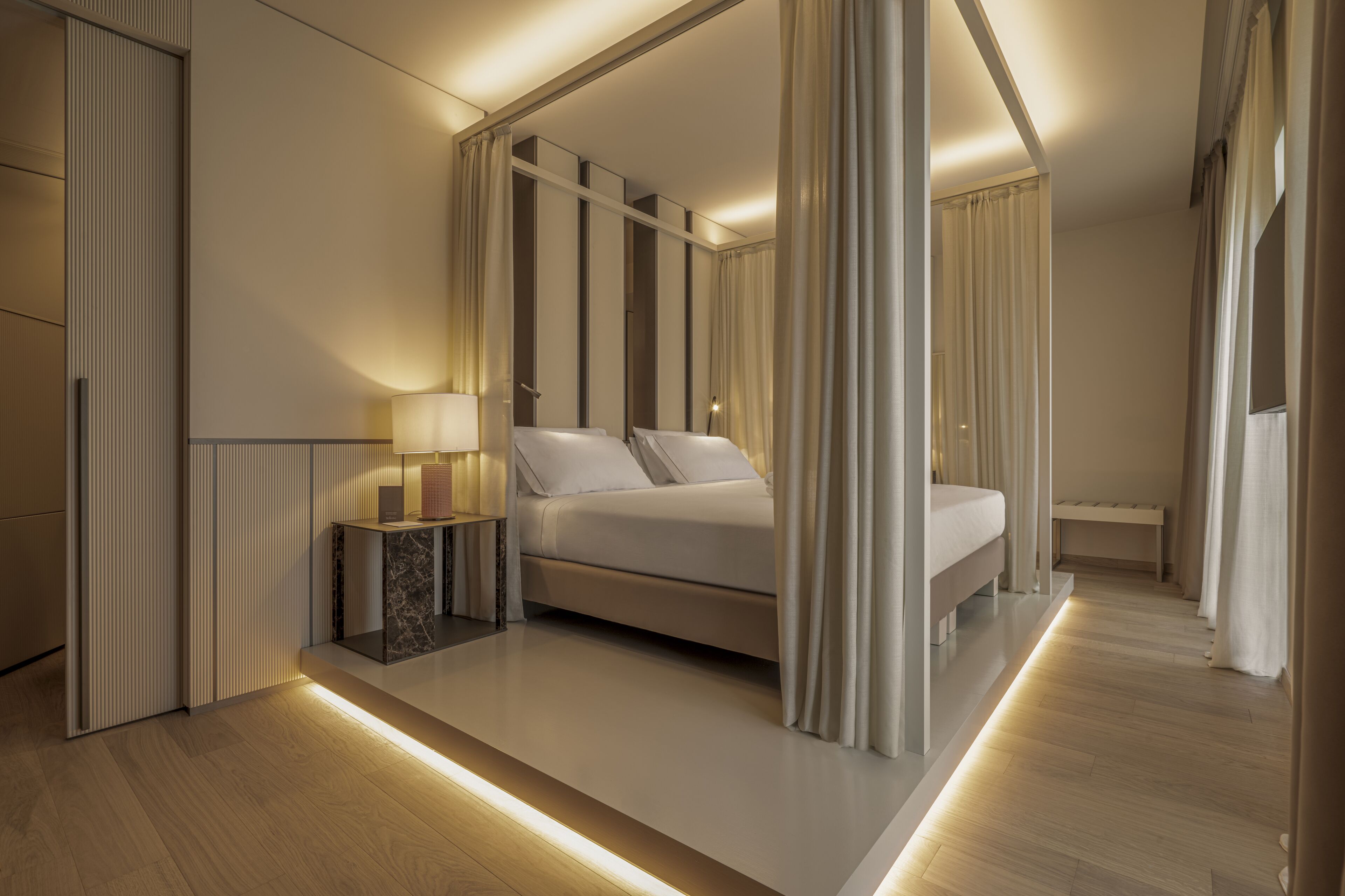 Une chambre d’hôtel moderne avec un grand lit, des tables de chevet et une vue sur la ville.