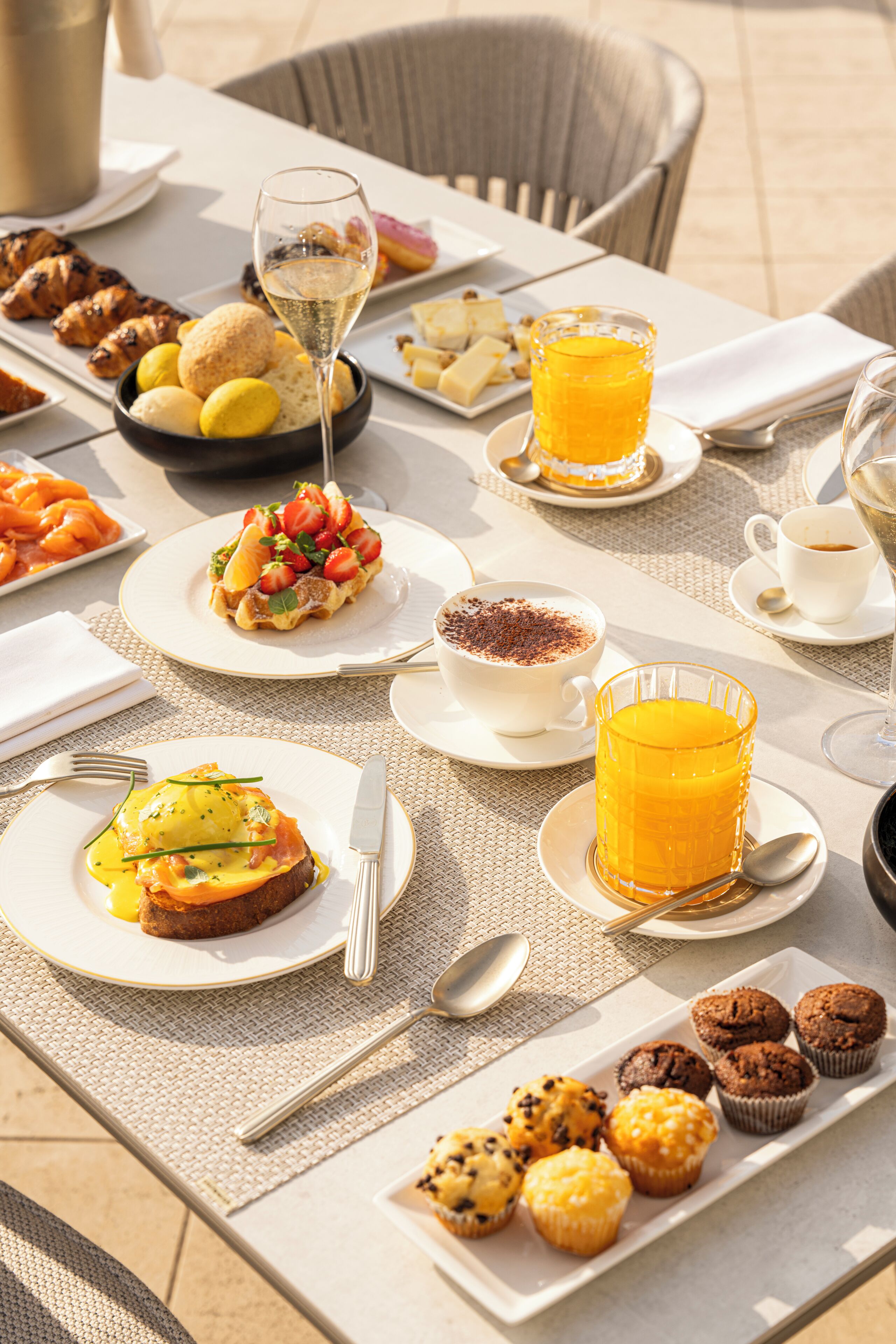 A table set with breakfast items including croissants, muffins, and a glass of orange juice.