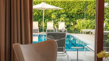 Habitación con vista a una piscina al aire libre, una silla y una mesa.