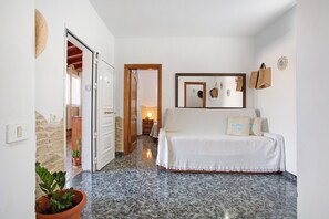 Un dormitorio con cama, espejo, un perchero de pared y una planta en maceta.