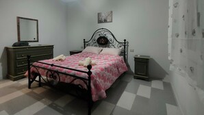 A bedroom with a bed, dresser, nightstands, and a wall-mounted mirror. - Holiday Home 'Villetta Roby' with Private Terrace, Private Garden and Air Conditioning (Marina di Modica)