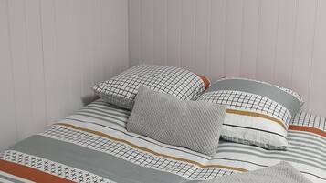 A neatly made bed with patterned bedding and pillows, a framed poster on the wall, and two framed artworks above the bed.
