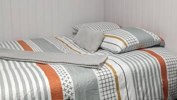Una camera da letto ordinata con un letto, cuscini, un comodino con una candela e una guida turistica.