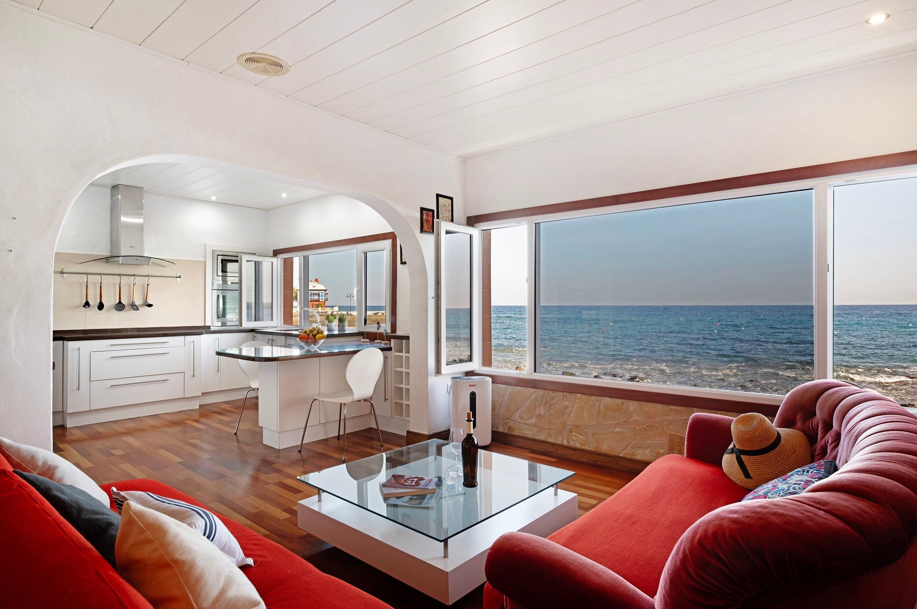 Un interior moderno con cocina, comedor y un amplio ventanal con vistas al mar.