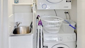 A compact laundry area with a washing machine, a dryer, a sink, and a shelf with a bottle of detergent. - Groovy & Cool~1Bed/1Bath/1Car~Close to everything! (Bowen Hills)