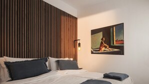 Een moderne hotelkamer met een bed, een houten paneelwand, een schilderij en een wandlamp.