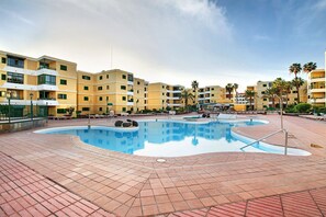 A swimming pool area with tiled flooring, a pool, and multi-story buildings in the background. - Loft Wheelchair Accessible Las Olas (San Bartolome de Tirajana)