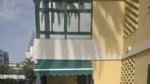 Ein Gebäude mit einer grünen Markise, Sitzgelegenheiten im Freien mit weißen Stühlen und einer Rasenfläche.